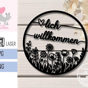 Könnte beinhalten: Schwarzes lasergeschnittenes Holzschild mit den deutschen Worten "lich willkommen" und einem Herzsymbol. Das Schild hat unten ein Blumendesign mit verschiedenen Blumen und Blättern. Das Schild ist kreisförmig.