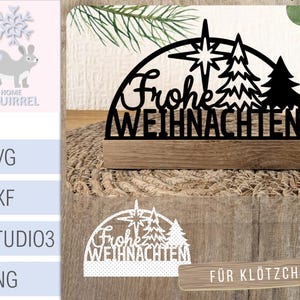 May include: Black laser-cut wooden Christmas decoration with the German phrase "Frohe Weihnachten" (Merry Christmas). The design includes a star and stylized Christmas trees, mounted on a wooden base.