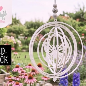 May include: A white 3D-printed hanging kinetic sculpture featuring concentric rings and a central butterfly design. The ornament is suspended by a string with two spherical beads, one plain white and one speckled grey, at the top.