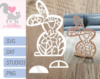 May include: A white paper cutout of a bunny rabbit with floral details. The bunny is standing on a wooden surface. The bunny is a 3D design with a stand.