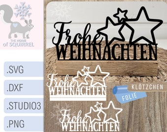 Op de afbeelding: Een zwart-wit digitaal ontwerp met de Duitse zin "Frohe Weihnachten" met drie sterren. Het ontwerp wordt getoond op een houten oppervlak met de woorden "Klötzchen Folie" in blauw en wit.