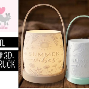 May include: Two ceramic lanterns with arched handles. One is beige, the other is white. Both have a floral and sun design with the words "Summer Vibes". The lanterns are lit from within, creating a warm glow.