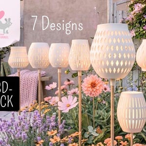 May include: Seven white outdoor lanterns with various cut-out designs are displayed in a garden setting. The lanterns are mounted on wooden poles and surrounded by colorful flowers. The text "7 Designs" is visible.