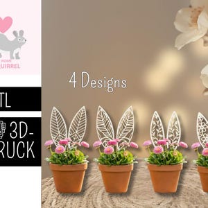 Può includere: Quattro vasi in terracotta con una piccola pianta con fiori rosa e decorativi picchetti bianchi a forma di orecchie di coniglio. L'immagine include il testo "4 Designs" e un logo con uno scoiattolo e la scritta "The Home of Squirrel".