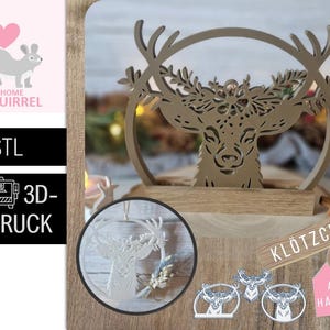 May include: A wooden deer head silhouette with antlers, set within a circular frame. The design is laser-cut and sits on a wooden base. Additional deer head ornaments and a tag are also visible.