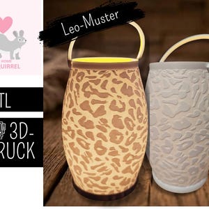 Könnte beinhalten: Zwei dekorative Laternen mit Griff. Eine Laterne hat ein beiges Leopardenmuster, die andere ist weiß. Der Text auf dem Bild lautet "Leo-Muster" und "3D-DRUCK". Das Bild enthält auch eine Eichhörnchen-Grafik.