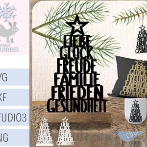 Puede incluir: Una exhibición de varias decoraciones de árbol de Navidad de madera negra con las palabras alemanas "Liebe, Glück, Freude, Familie, Frieden, Gesundheit" (Amor, Suerte, Alegría, Familia, Paz, Salud). Incluye una almohada, una taza y adornos colgantes.