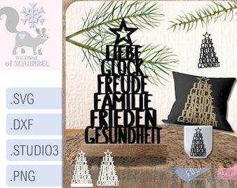 May include: A display of various black wooden Christmas tree decorations with the German words "Liebe, Glück, Freude, Familie, Frieden, Gesundheit" (Love, Luck, Joy, Family, Peace, Health). Includes a pillow, mug, and hanging ornaments.