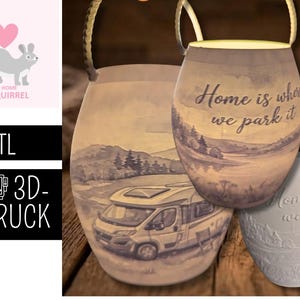 May include: Three ceramic lanterns with a camping theme. The largest lantern has a landscape scene with a camper van and the text "Home is where we park it." The other two lanterns have the same text. The image also includes a squirrel logo and text that says ".STL 3D-DRUCK."