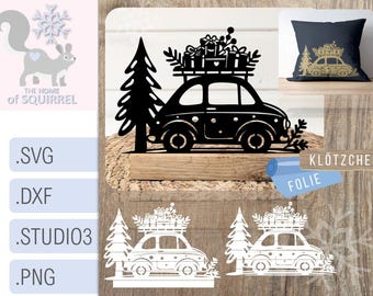 May include: Black and white silhouette of a car with a Christmas tree and presents on top. The car is on a wooden base. The text "Klötzchen Folie" is on the base.