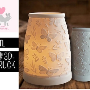 Könnte beinhalten: Zwei zylindrische Kerzenhalter aus Keramik in Off-White mit Schmetterlings- und Blumenreliefmustern. Einer ist von innen beleuchtet und zeigt das Design. Der andere ist unbeleuchtet. Das Bild enthält auch ein Logo mit einem Eichhörnchen und dem Text ".STL 3D-DRUCK."