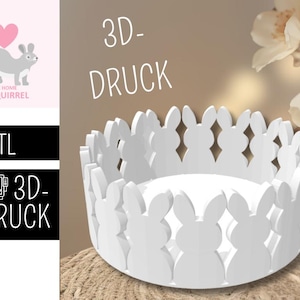 Może przedstawiać: Biała miska drukowana w 3D z motywem królika na obrzeżu. Misa stoi na tkanej powierzchni. Widoczny jest tekst "3D-DRUCK". Obraz zawiera również logo wiewiórki.