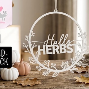 Könnte beinhalten: Ein weißer, kreisförmiger Hängeschmuck mit dem deutschen Schriftzug Hallo HERBST in der Mitte, umgeben von einem filigranen Scherenschnitt-Design aus Herbstblättern, Beeren und Zweigen. Das Ornament ist an einer dünnen Bandschlaufe befestigt.