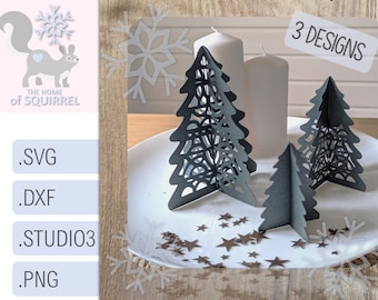May include: Three black paper Christmas tree designs with intricate cutouts. The trees are on a white plate with brown star confetti. The text "3 DESIGNS" is in the upper right corner of the image.