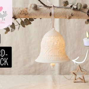 May include: A white 3D-printed bell ornament featuring an embossed winter forest scene and script text. The bell hangs from a light pink ribbon and includes a small internal light source, with a white tea light candle shown to the side.