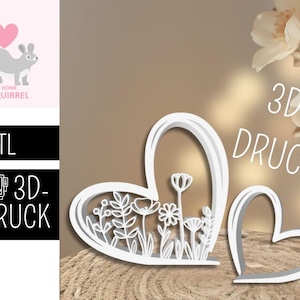 Könnte beinhalten: Weiße 3D-gedruckte herzförmige Dekoration mit floralem Design. Das Design umfasst verschiedene Blumen und Blätter. Das Bild zeigt auch eine kleinere Herzform und den Text "3D-DRUCK".