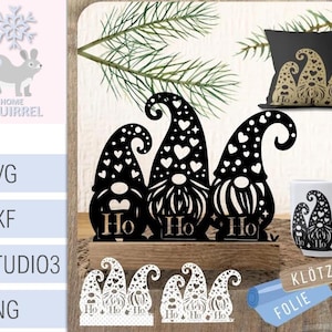 Può includere: Decorazioni natalizie a forma di gnomi neri ritagliati con motivi a cuore e a pois, e la parola "Ho". Include un cuscino, una tazza e piccoli ritagli con lo stesso design. Il logo The Home of Squirrel si trova in alto a sinistra.