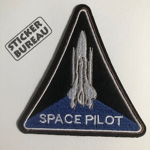 May include: A black triangular patch with a white embroidered space shuttle and the text "SPACE PILOT" in white on a blue background.