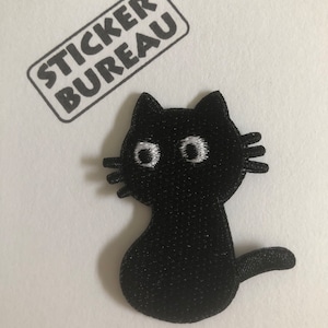 May include: A black cat patch with white embroidered eyes and whiskers. The patch is in the shape of a sitting cat with a curved tail. The text "STICKER BUREAU" is printed above the cat patch in a rectangular shape.