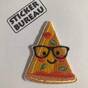 May include: A yellow embroidered pizza slice with a smiling face wearing black framed glasses. The pizza has red pepperoni, green peppers, and a white crust.
