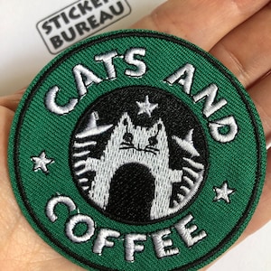 May include: Green and black embroidered patch with a white cat and the text "Cats and Coffee" in white.