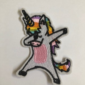 Puede incluir: Parche bordado para planchar de un unicornio blanco con una melena y cola arcoíris, haciendo el dab.