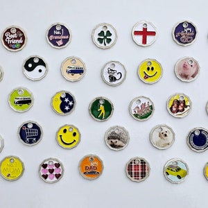 May include: Assortment of colourful metal keyrings with various designs, including animals, vehicles, symbols, and text. The keyrings are round and have a silver-coloured metal ring.