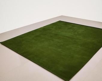 Puede incluir: Una alfombra verde rectangular grande. La alfombra es de un color verde sólido y vibrante y parece estar hecha de un material suave y afelpado. La alfombra está colocada sobre un suelo de baldosas de color claro.