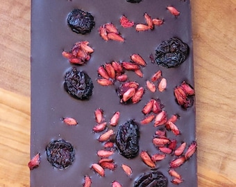 Tableta de chocolate negro con granada y arándanos, elaborada artesanalmente, orgánica, vegana, sin lácteos ni gluten, sin azúcar refinada, 75% chocolate negro, sin OMG, de comercio justo.