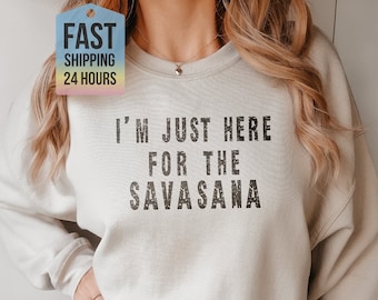 Op de afbeelding: Een licht beige sweatshirt met de tekst "I'm just here for the Savasana" in zwart gedrukt.