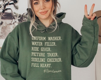 Può includere: Felpa con cappuccio verde con il testo "UNIFORM WASHER. WATER FILLER. RIDE GIVER. PICTURE TAKER. SIDELINE CHEERER. FULL HEART. #Sportsmom" stampato sul davanti.