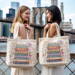 May include: Two off-white tote bags with a floral and book design. Each bag features a stack of books with titles and the text "WRITE YOUR FAVORITE BOOK NAME". The bags have cream-colored straps and are held by two people.