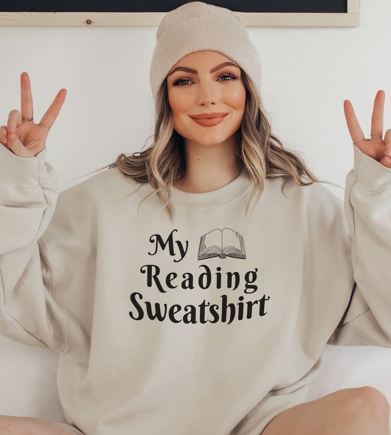 May include: A beige sweatshirt with the text "My Reading Sweatshirt" and a black and white illustration of an open book.