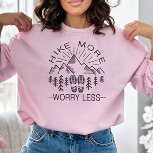 May include: Pink sweatshirt with a black graphic design that says "Hike More Worry Less" with a mountain range and footprints.