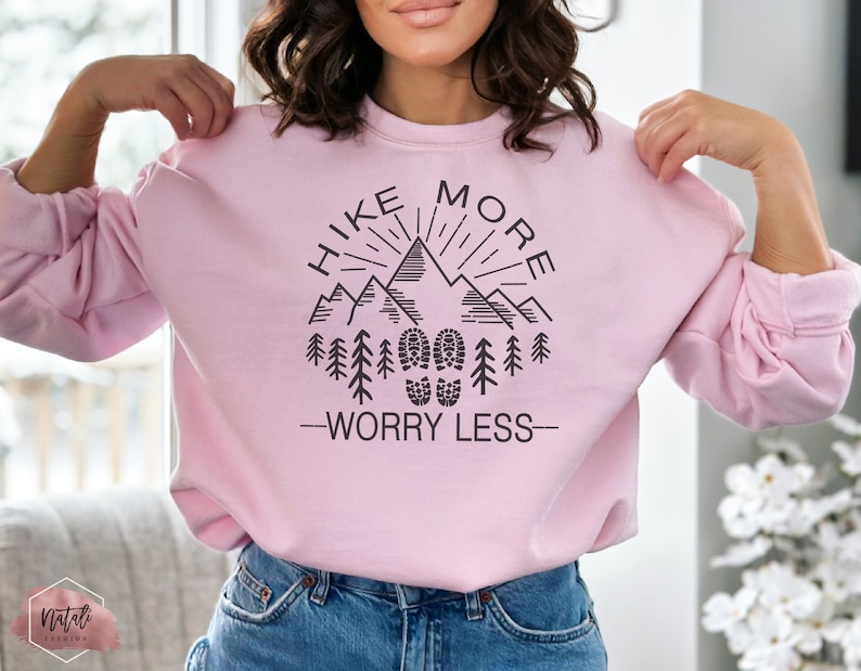 May include: Pink sweatshirt with a black graphic design that says "Hike More Worry Less" with a mountain range and footprints.