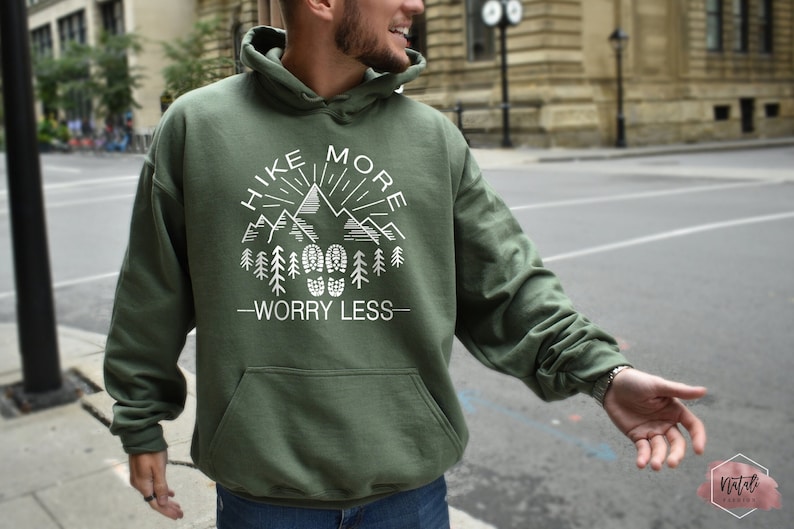 May include: A green hooded sweatshirt with a white graphic design that says "Hike More Worry Less" with a mountain range and a sun with rays.