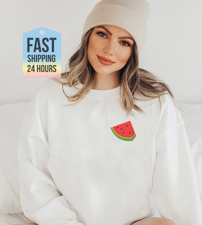 May include: White sweatshirt with a watermelon graphic on the front. The watermelon is red with black seeds and a green rind.