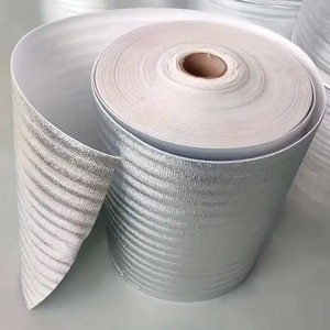 May include: A roll of silver-colored insulation material with a white backing. The insulation is corrugated and has a reflective surface.