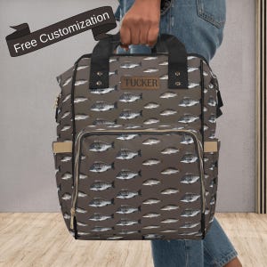May include: A brown backpack with a fish pattern, featuring a front pocket and side pockets. The backpack has black handles and a leather patch with the name "TUCKER". The text "Free Customization" is on a banner.