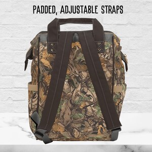 The back side of our mens camo diaper bag shows padded, adjustable shoulder straps in a brown color.