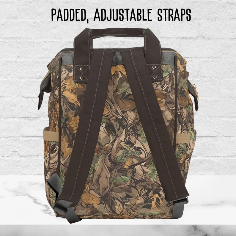 The back side of our mens camo diaper bag shows padded, adjustable shoulder straps in a brown color.