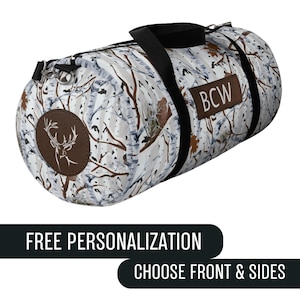 May include: A white and brown duffel bag with a birch tree pattern. The bag has a black strap and handles, and a brown patch with the initials "BCW". A brown circular patch with a deer head is on the side. The text "FREE PERSONALIZATION" and "CHOOSE FRONT & SIDES" are below.