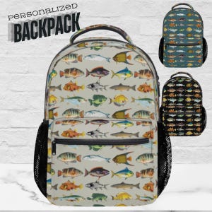 Puede incluir: Una mochila con un estampado de peces multicolores sobre un fondo gris claro. El diseño incluye peces en tonos naranja, amarillo, azul y verde. Tiene un bolsillo lateral de malla negro y un bolsillo frontal con cremallera. El texto "PERSONALIZED BACKPACK" está impreso en la parte superior.