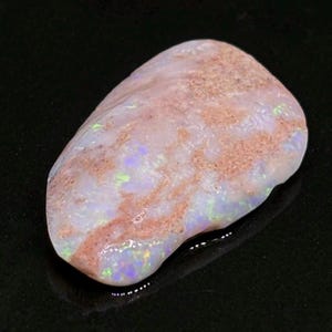 May include: A white opal with a pink and brown matrix. The opal has a light iridescent sheen.