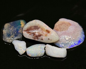 May include: A collection of six rough opal stones in various shapes and sizes. The stones are a mix of white, brown, and blue.