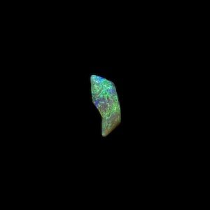 May include: A polished opal gemstone with a vibrant display of colour. The stone features a mix of green, blue, and purple hues, with a swirling pattern. The opal is set against a black background.