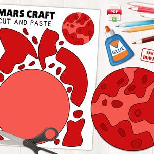 May include: A Mars craft cut-and-paste activity set. The set includes a sheet with a large red circle and cut-out shapes, a completed Mars illustration, a glue bottle, colored pencils, and scissors. The words "Mars Craft Cut and Paste" are at the top.