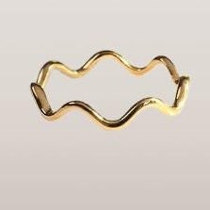 Peut inclure: Une bague dorée avec un motif ondulé. La bague présente un motif continu et ondulé, créant une forme fluide et organique. La bague est faite d'un métal brillant et réfléchissant.