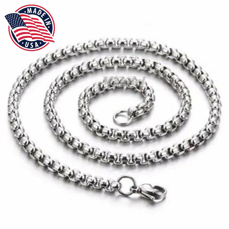 Op de afbeelding: Een zilveren ketting met een karabijn sluiting. De ketting is gemaakt van kleine, ronde schakels.
