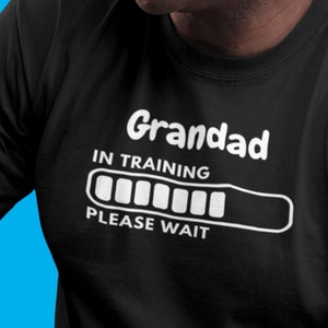 May include: Black t-shirt with white text that reads "Grandad in Training" and a progress bar that says "Please Wait".